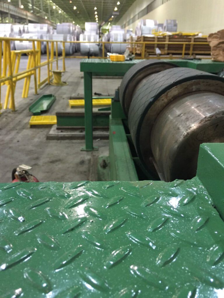 Mill machinery with a large steel drum set on a yellow platform
